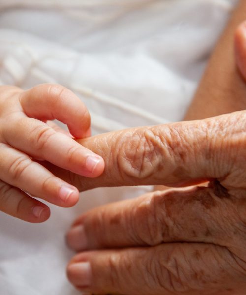 Baby holding finger from great grandmother